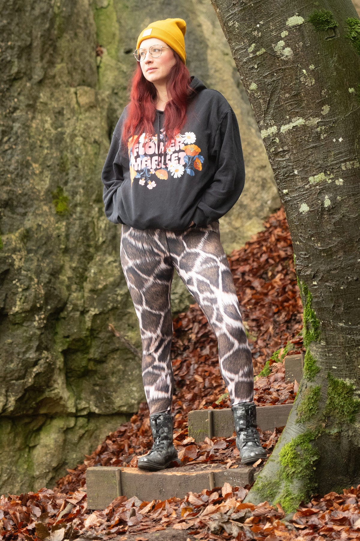 High-Waist-Damen-Leggings Giraffe von Bachblatt mit braunem Giraffenmuster – Am Model mit schwarzem Hoodie und gelber Mütze auf einer Waldtreppe.