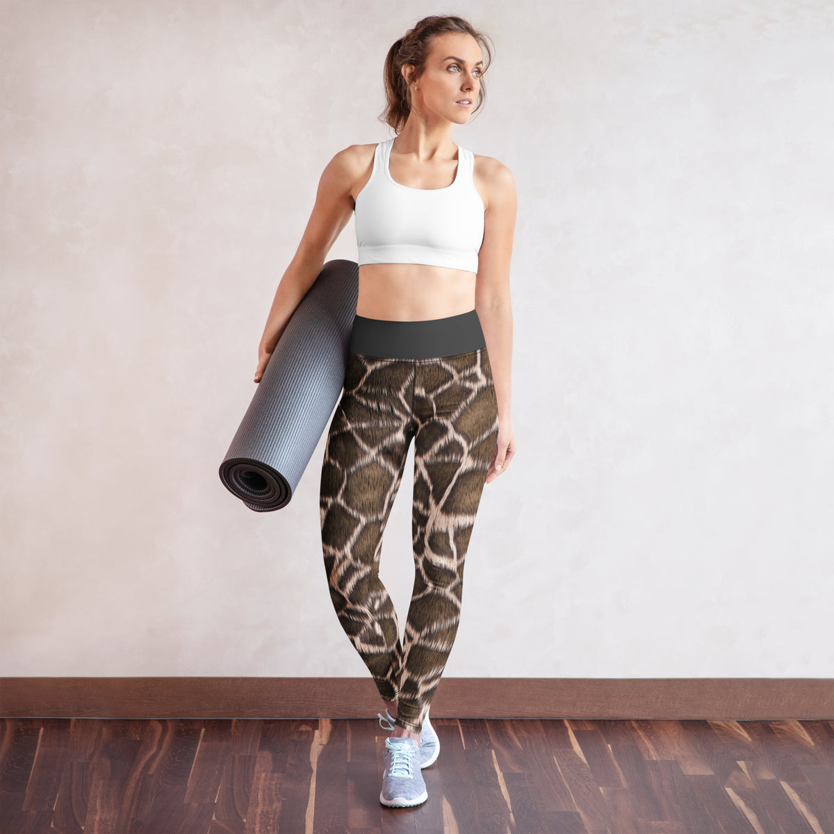 High-Waist-Damen-Leggings Giraffe von Bachblatt mit braunem Giraffenmuster – Am Model mit Yogamatte vor einer hellen Wand.