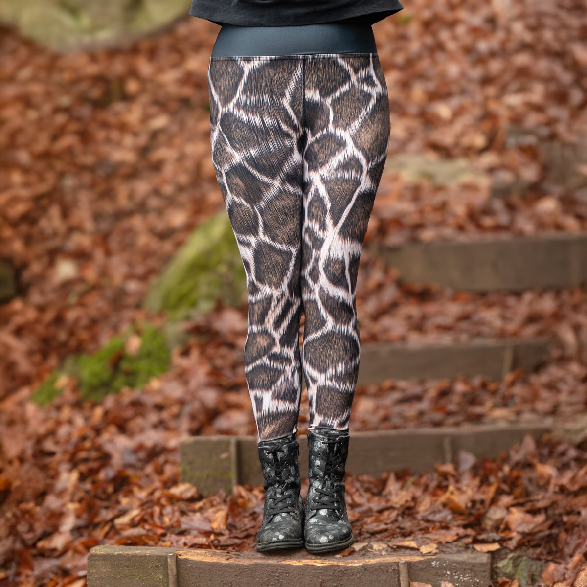 High-Waist-Damen-Leggings Giraffe von Bachblatt mit braunem Giraffenmuster – Nahaufnahme am Model mit Stiefeln auf einer laubbedeckten Waldtreppe.